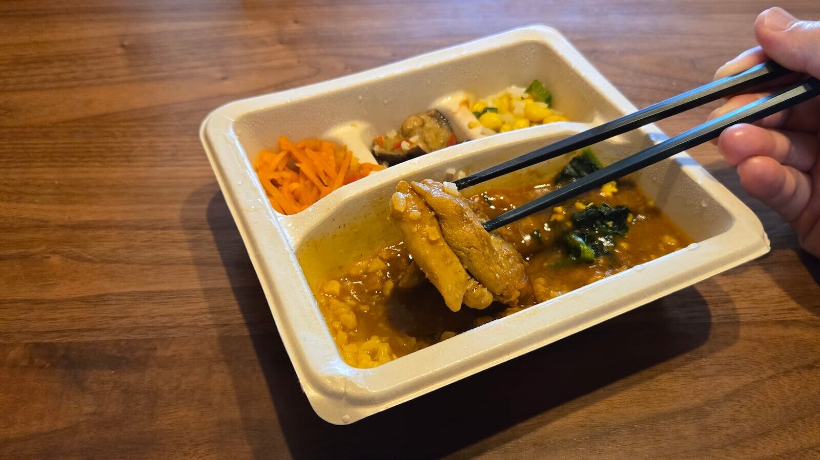 ナッシュ「バターチキンカレー」の鶏肉を箸で持ち上げた写真。ボリュームや断面が確認できる。