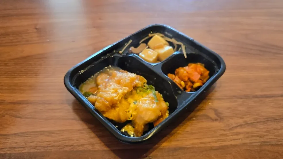 ワタミ宅食ダイレクト〈みちのく清流どりのチキン南蛮〉と副菜2種を斜め上から撮影した黒トレー