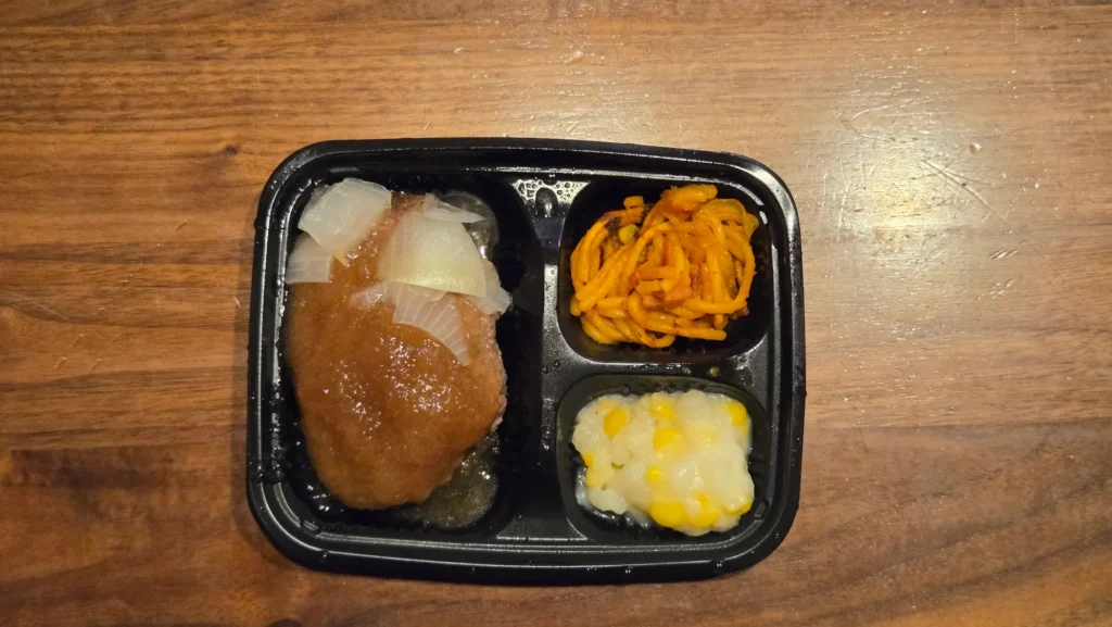 加熱後の「オニオンソースの和風ハンバーグ」弁当を真上から撮影。主菜と副菜2品の配置が分かる。