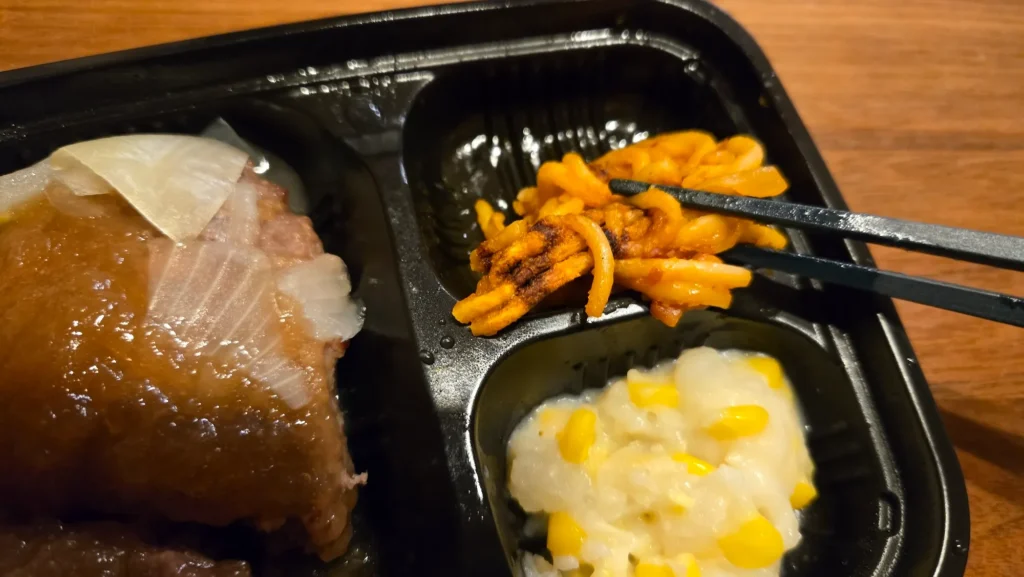トマトソーススパゲッティの焦げ目が分かるクローズアップ。手前にコーンポテトサラダ。